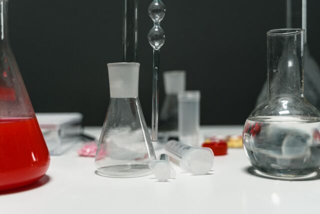 Eprubete și vase de laborator așezate pe o masă de lucru, pregătite pentru un experiment