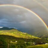 Curcubeu dublu deasupra unui câmp verde, după o ploaie de vară