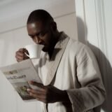 Persoană care citește atent un ziar la o masă, cu o ceașcă de cafea alături