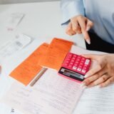Proprietar de mic atelier care calculează costurile la un birou, cu facturi și un calculator