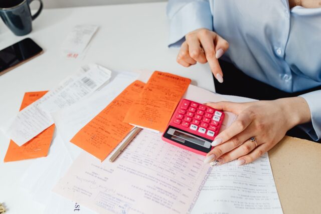 Proprietar de mic atelier care calculează costurile la un birou, cu facturi și un calculator