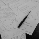 Cartonașe de studiu scrise de mână, așezate pe un birou lângă un caiet deschis