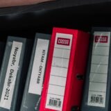 Dosare etichetate pe categorii, aranjate ordonat pe un raft de acasă